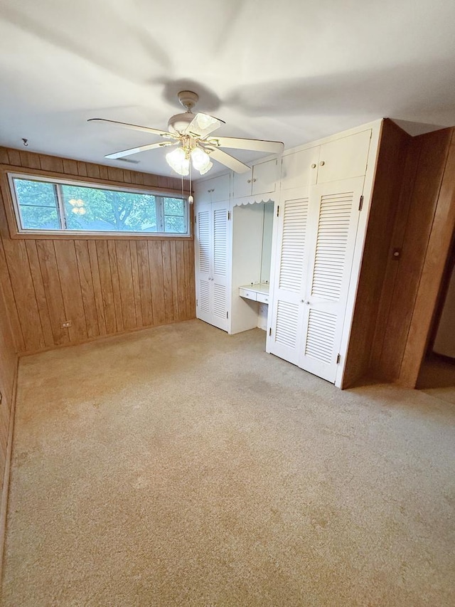 942 W Villa Dr, Des Plaines, IL 60016 - unfurnished bedroom featuring wood walls, light carpet, two closets, and a ceiling fan
