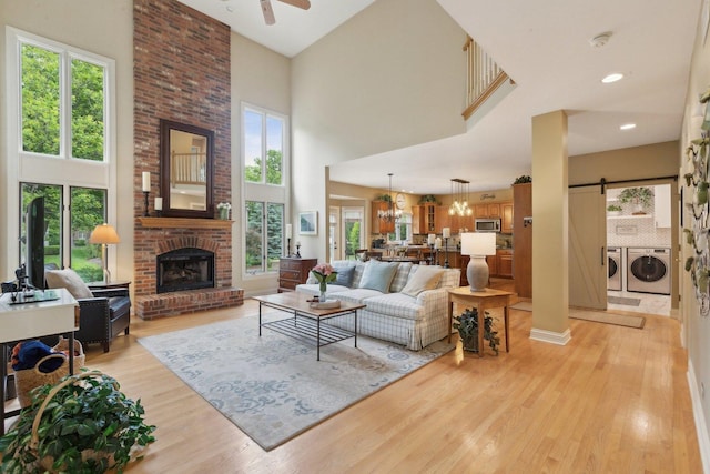 2156 Red Maple Ln, Aurora, IL 60502 - living room with washer and clothes dryer, a high ceiling, light wood finished floors, a ceiling fan, and a brick fireplace