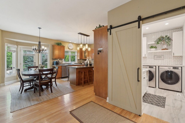 2156 Red Maple Ln, Aurora, IL 60502 - dining room with separate washer and dryer, a chandelier, a barn door, light wood finished floors, and baseboards