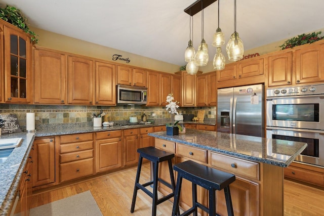 2156 Red Maple Ln, Aurora, IL 60502 - kitchen featuring appliances with stainless steel finishes, a center island, glass insert cabinets, dark stone countertops, and light wood-type flooring