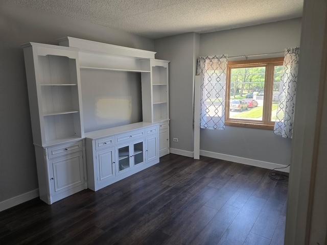 4739 W 105th Pl Unit 101, Oak Lawn, IL 60453 - unfurnished living room with dark wood-style flooring, baseboards, and a textured ceiling