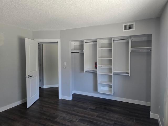 4739 W 105th Pl Unit 101, Oak Lawn, IL 60453 - unfurnished bedroom featuring a closet, dark wood-style flooring, a textured ceiling, and baseboards