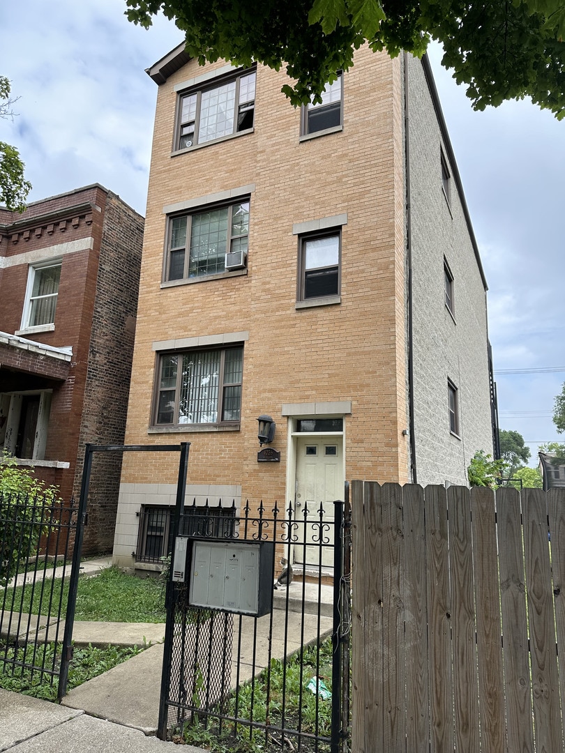 4036 W Gladys Ave, Chicago, IL 60624 - view of front of home with brick siding, a fenced front yard, a gate, and cooling unit