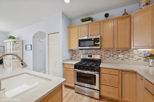 1736 Francis Dr, Pingree Grove, IL 60140 - kitchen featuring stainless steel appliances, a sink, arched walkways, backsplash, and light wood-style flooring