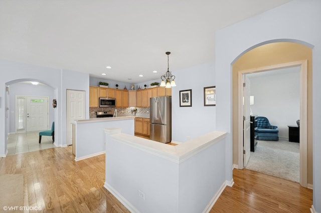 1736 Francis Dr, Pingree Grove, IL 60140 - kitchen featuring stainless steel appliances, arched walkways, light wood finished floors, a center island, and light countertops
