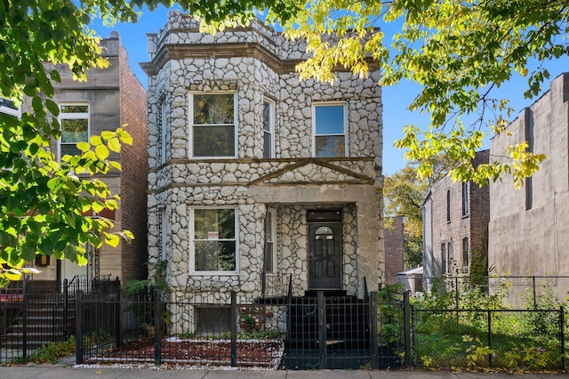 4321 W Maypole Ave, Chicago, IL 60624 - view of front of property featuring stone siding, a fenced front yard, and a gate