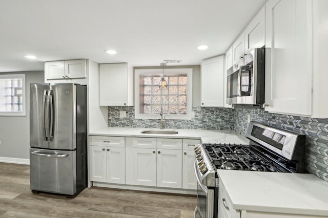 7801 S Honore St, Chicago, IL 60620 - kitchen featuring stainless steel appliances, a sink, white cabinets, tasteful backsplash, and light wood-style floors