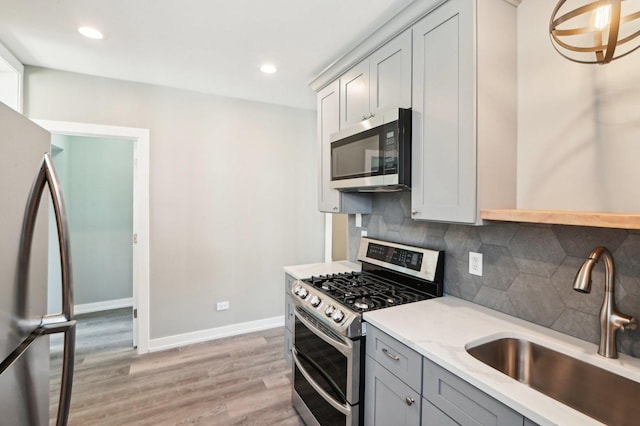 7801 S Honore St, Chicago, IL 60620 - kitchen featuring stainless steel appliances, a sink, gray cabinetry, light wood-style flooring, and decorative backsplash