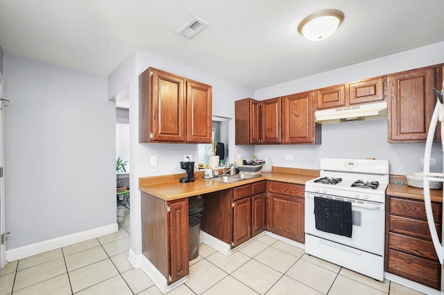 1026 Bothwell Ct, Bolingbrook, IL 60440 - kitchen featuring white gas stove, under cabinet range hood, light countertops, light tile patterned floors, and brown cabinets