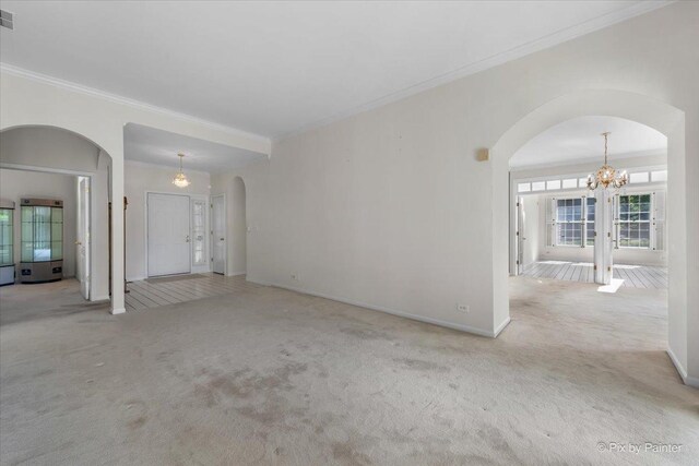324 Torrington Dr, Bloomingdale, IL 60108 - unfurnished living room featuring arched walkways, ornamental molding, carpet flooring, a chandelier, and baseboards