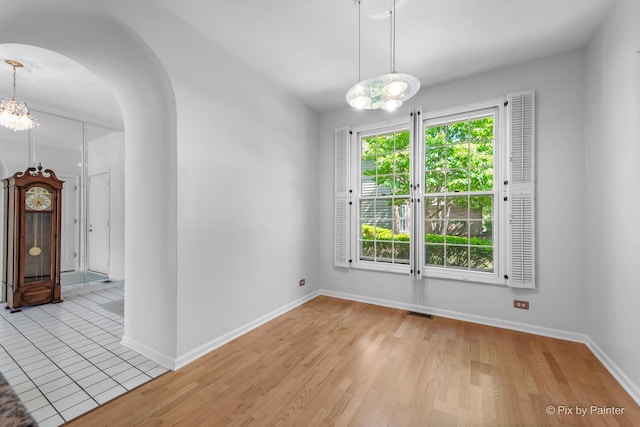 324 Torrington Dr, Bloomingdale, IL 60108 - empty room with arched walkways, baseboards, wood finished floors, and a chandelier