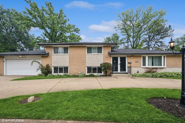 9047 Crawford Ave, Skokie, IL 60076 - tri-level home featuring concrete driveway, brick siding, a front yard, and an attached garage