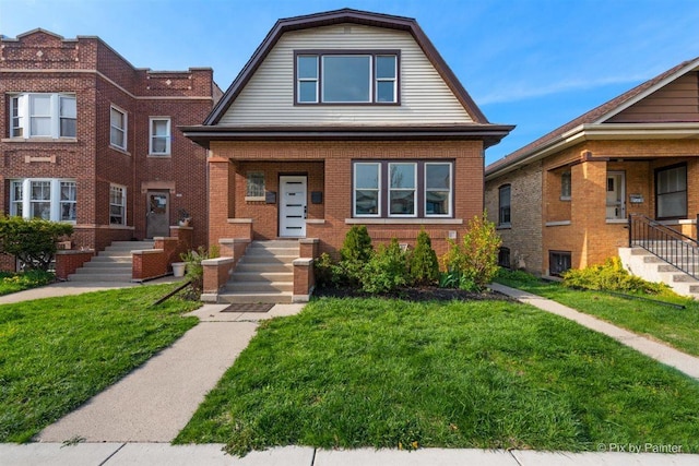 4846 W Roscoe St, Chicago, IL 60641 - view of front facade with a gambrel roof, a front yard, and brick siding