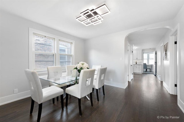 4846 W Roscoe St, Chicago, IL 60641 - dining space featuring arched walkways, dark wood-style flooring, and baseboards