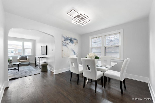 4846 W Roscoe St, Chicago, IL 60641 - dining room featuring arched walkways, dark wood-style floors, and baseboards