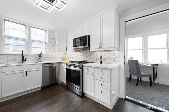 4846 W Roscoe St, Chicago, IL 60641 - kitchen with stainless steel appliances, a sink, decorative backsplash, white cabinets, and dark wood-style flooring