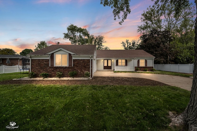 1245 W Lotus Ln, Kankakee, IL 60901 - ranch-style house featuring a trampoline, concrete driveway, brick siding, and covered porch