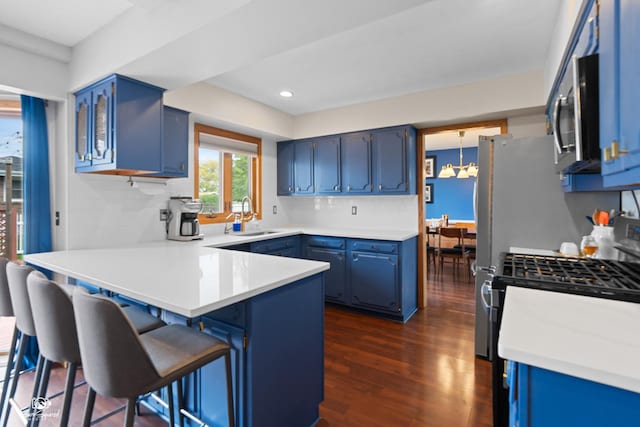1245 W Lotus Ln, Kankakee, IL 60901 - kitchen with a peninsula, a sink, blue cabinets, dark wood-style flooring, and decorative backsplash
