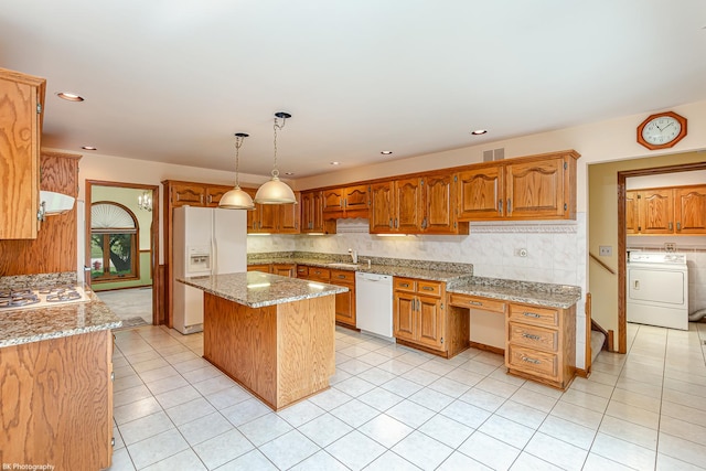 18633 Swan Dr, Mokena, IL 60448 - kitchen with washer / dryer, white appliances, a sink, light stone counters, and a center island
