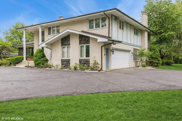 69 Graymoor Ln, Olympia Fields, IL 60461 - view of front of house with a chimney, asphalt driveway, board and batten siding, an attached garage, and brick siding