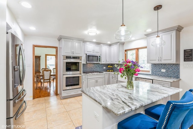 69 Graymoor Ln, Olympia Fields, IL 60461 - kitchen featuring stainless steel appliances, backsplash, a kitchen bar, light stone counters, and light tile patterned floors