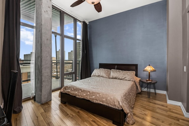 1000 W Leland St Unit 9B, Chicago, IL 60640 - bedroom with wood-type flooring, baseboards, a view of skyline, expansive windows, and ceiling fan