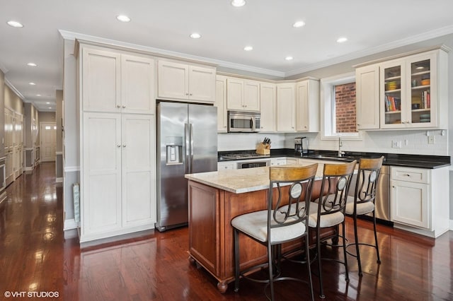 5051 N Clark St Unit 2S, Chicago, IL 60640 - kitchen with stainless steel appliances, crown molding, a kitchen island, decorative backsplash, and glass insert cabinets