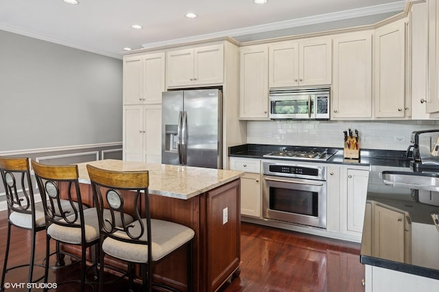 5051 N Clark St Unit 2S, Chicago, IL 60640 - kitchen featuring appliances with stainless steel finishes, crown molding, recessed lighting, a kitchen bar, and dark wood-style floors