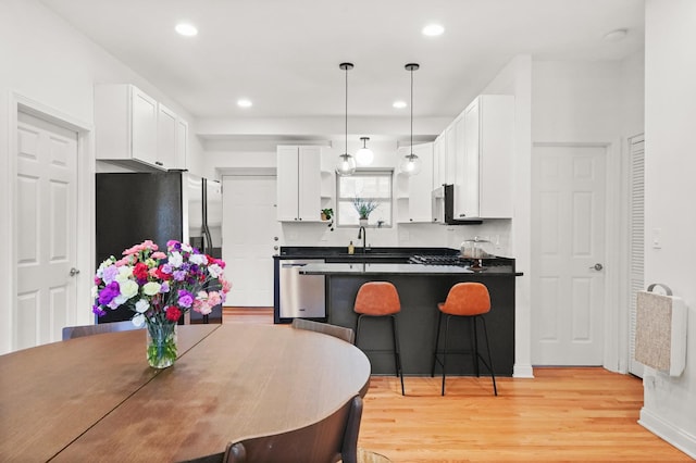 3406 W Medill Ave Unit 1, Chicago, IL 60647 - kitchen featuring appliances with stainless steel finishes, dark countertops, a peninsula, light wood-style floors, and open shelves