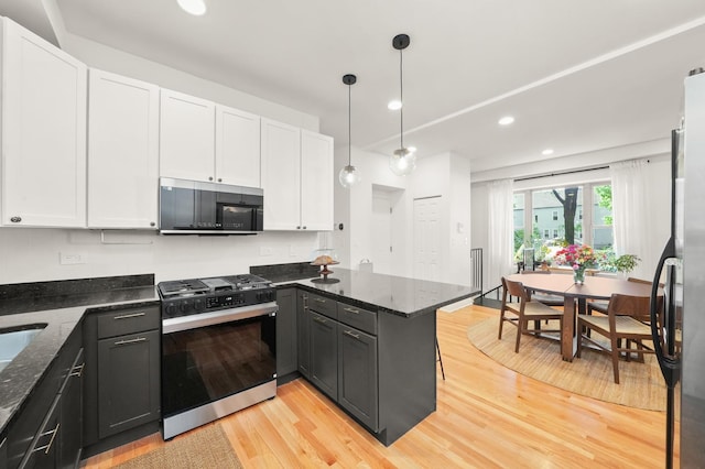 3406 W Medill Ave Unit 1, Chicago, IL 60647 - kitchen with range with gas cooktop, a peninsula, white cabinets, light wood-style flooring, and dark stone counters
