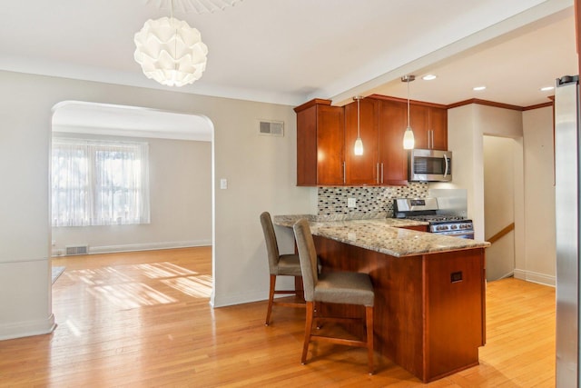 38 Northgate Rd, Riverside, IL 60546 - kitchen with stainless steel appliances, arched walkways, tasteful backsplash, brown cabinets, and light stone countertops