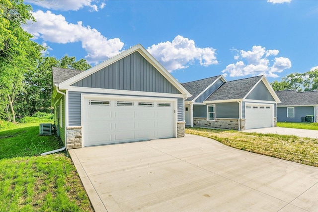 205 E Fairfield St, Fisher, IL 61843 - craftsman inspired home featuring board and batten siding, stone siding, a front yard, a shingled roof, and cooling unit