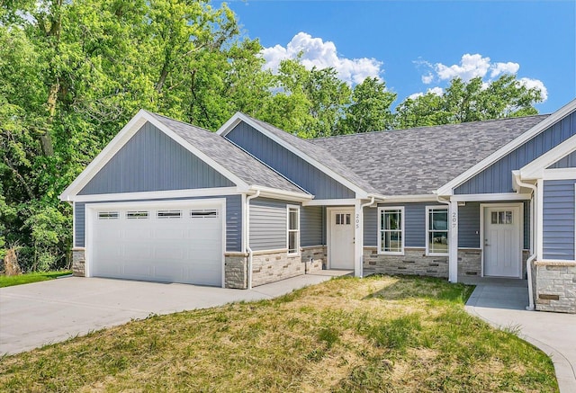 205 E Fairfield St, Fisher, IL 61843 - craftsman house featuring an attached garage, roof with shingles, concrete driveway, a front lawn, and stone siding