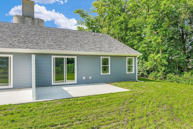 205 E Fairfield St, Fisher, IL 61843 - rear view of property featuring a patio area, a lawn, a chimney, and a shingled roof