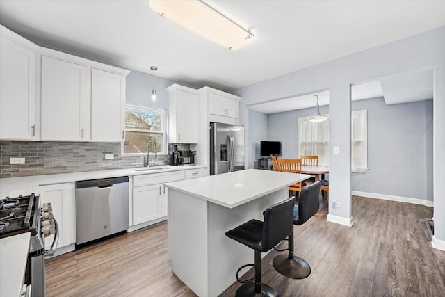 3534 Clarence Ave, Berwyn, IL 60402 - kitchen with appliances with stainless steel finishes, a sink, a kitchen bar, tasteful backsplash, and light wood-type flooring