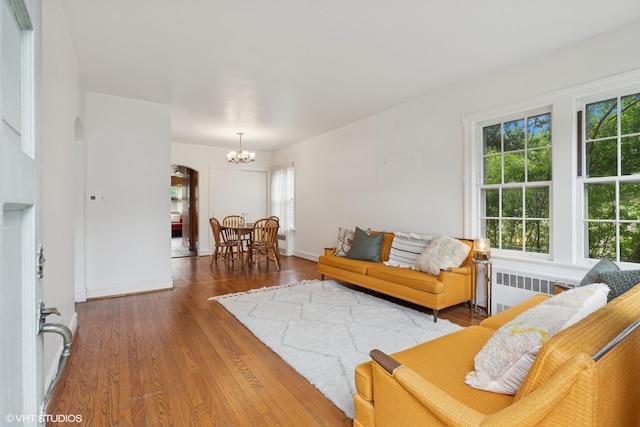 5748 N Lansing Ave, Chicago, IL 60646 - living room with arched walkways, a chandelier, radiator, wood finished floors, and baseboards