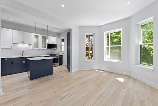 6233 S Woodlawn Ave Unit 2, Chicago, IL 60637 - kitchen with appliances with stainless steel finishes, light countertops, white cabinets, a kitchen island, and glass insert cabinets