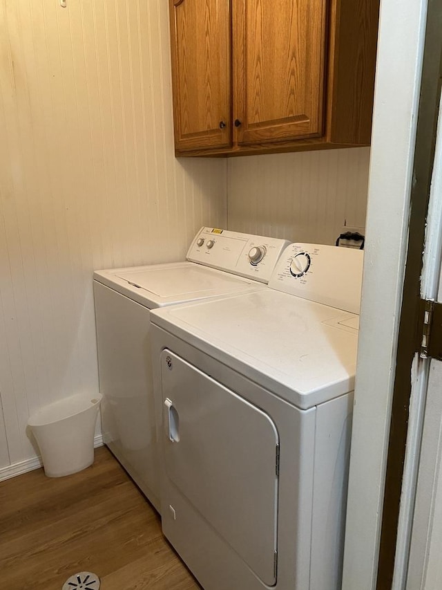 17612 71st Ct Unit 1N, Tinley Park, IL 60477 - laundry room with washing machine and dryer, light wood-style floors, cabinet space, wood walls, and baseboards