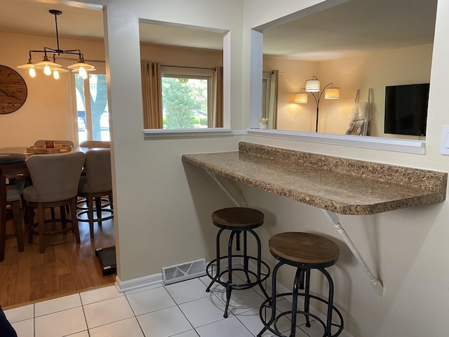 17612 71st Ct Unit 1N, Tinley Park, IL 60477 - kitchen featuring a breakfast bar, tile patterned flooring, dark countertops, and baseboards
