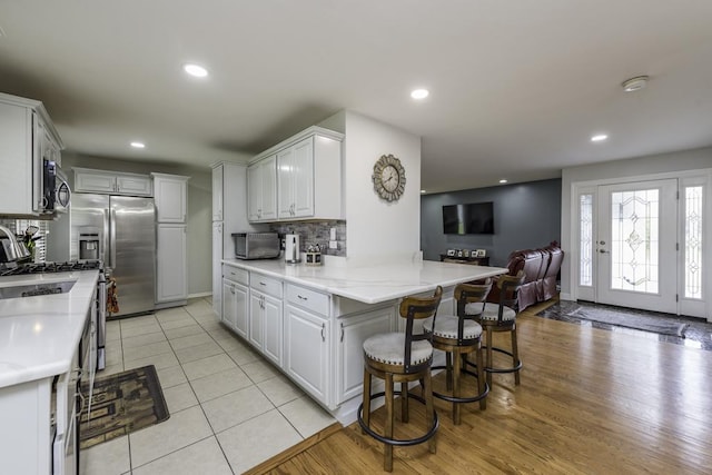 3106 Lebanon Ave, Zion, IL 60099 - kitchen featuring backsplash, a peninsula, a kitchen breakfast bar, stainless steel appliances, and white cabinets