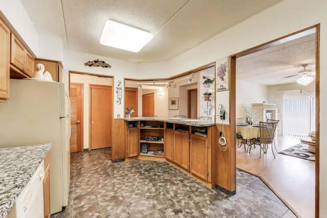 5555 N Cumberland Ave Unit 309, Chicago, IL 60656 - kitchen featuring freestanding refrigerator, a textured ceiling, a ceiling fan, brown cabinets, and light stone countertops