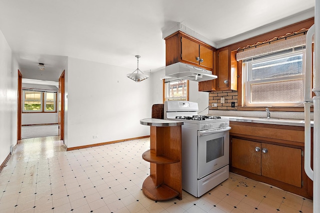 3840 S Wolcott Ave, Chicago, IL 60609 - kitchen with white range with gas cooktop, under cabinet range hood, brown cabinetry, baseboards, and light countertops