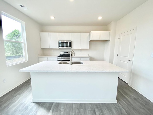 kitchen featuring appliances with stainless steel finishes, a sink, white cabinetry, baseboards, and dark wood-type flooring