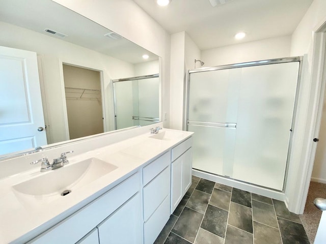 bathroom featuring a shower stall, double vanity, a spacious closet, and recessed lighting