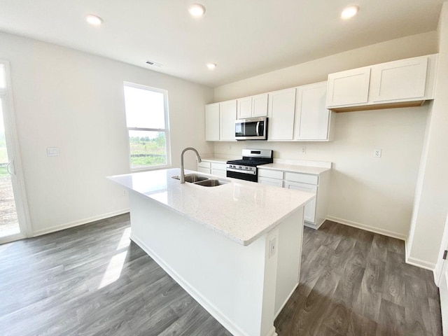 kitchen featuring appliances with stainless steel finishes, a sink, an island with sink, white cabinetry, and dark wood-type flooring