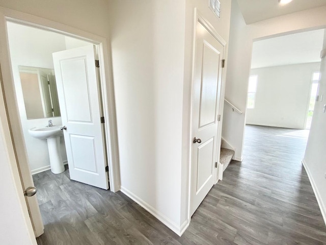 hall featuring wood finished floors, baseboards, stairway, and a sink