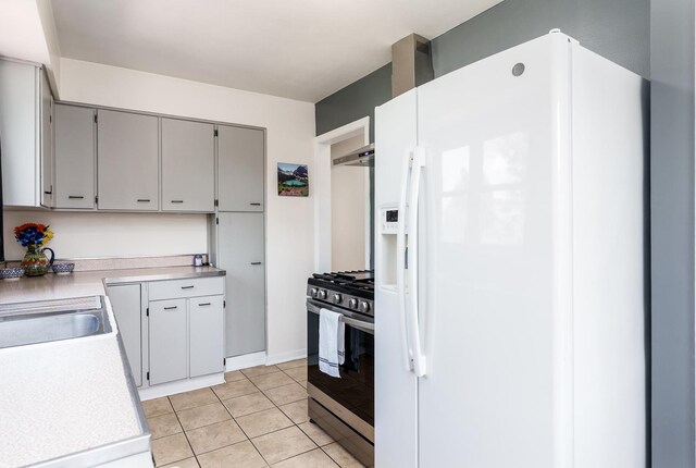 711 Parkside Dr, Rockford, IL 61108 - kitchen featuring white refrigerator with ice dispenser, stainless steel range with gas stovetop, wall chimney exhaust hood, light tile patterned floors, and light countertops