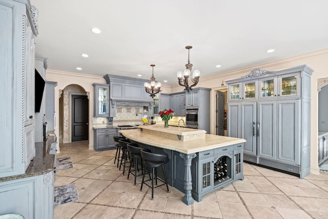 115 Carmela Ct, Bloomingdale, IL 60108 - kitchen with gray cabinets, arched walkways, a chandelier, ornamental molding, and a large island