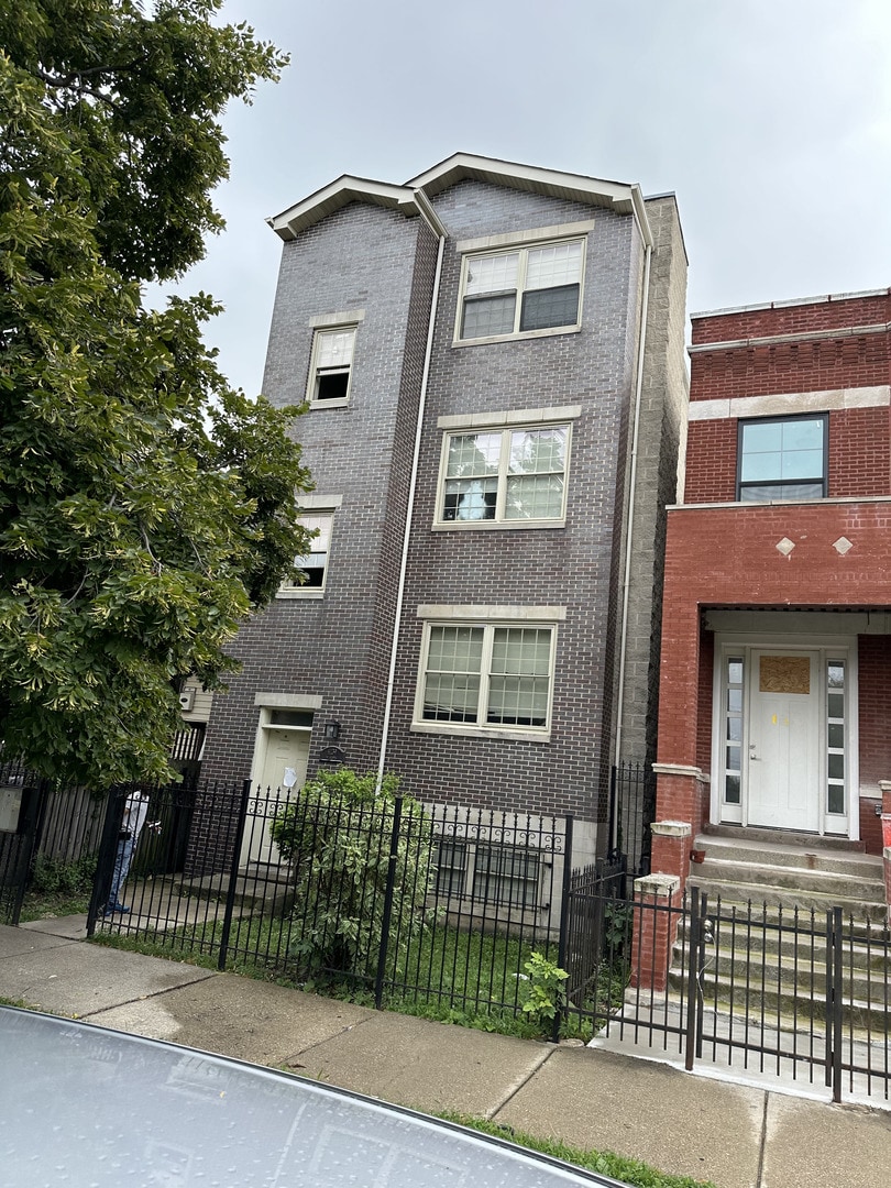 4139 W Gladys Ave, Chicago, IL 60624 - view of property featuring brick siding and a fenced front yard