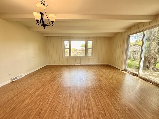 319 Triggs Ave, Elgin, IL 60123 - empty room with beam ceiling, wood finished floors, healthy amount of natural light, and a chandelier